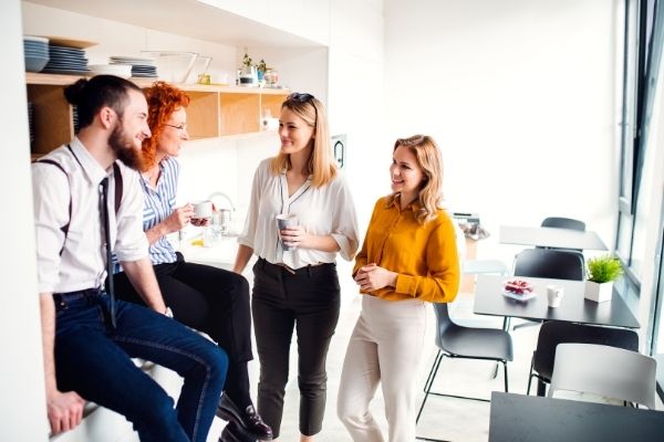 office workers standing in kitchen near microwave